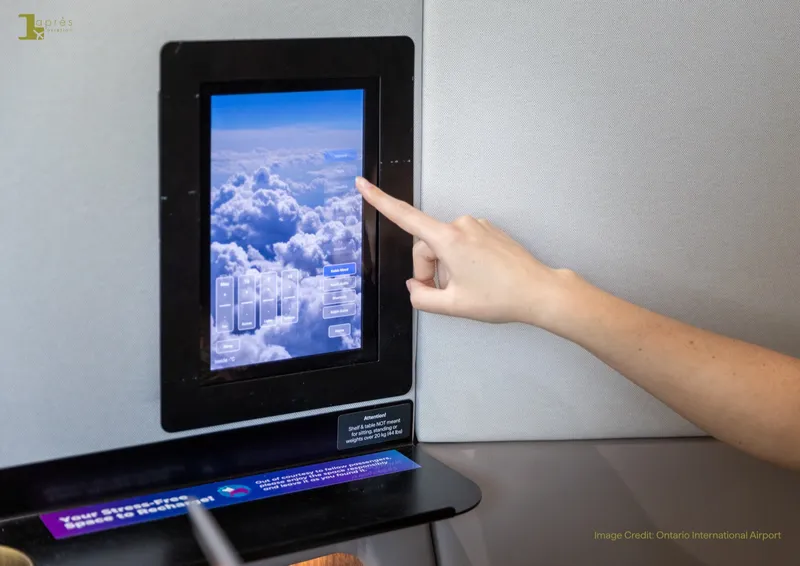 A traveller's hand selecting an ambient sky scene on the integrated touchscreen inside a Kabin by Après Aviation pod.